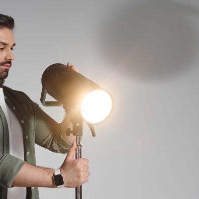 Man adjusts studio lighting while preparing for a creative photography session in modern studio